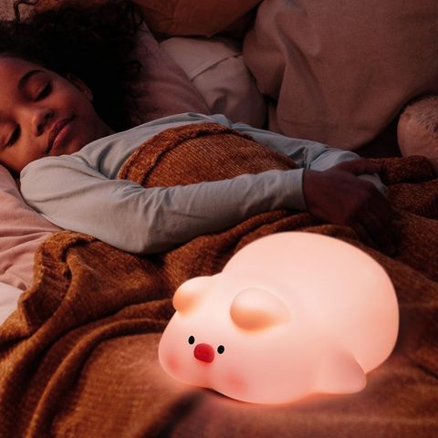 Fille dormant près de veilleuse enfant cochon, créant une ambiance de sérénité